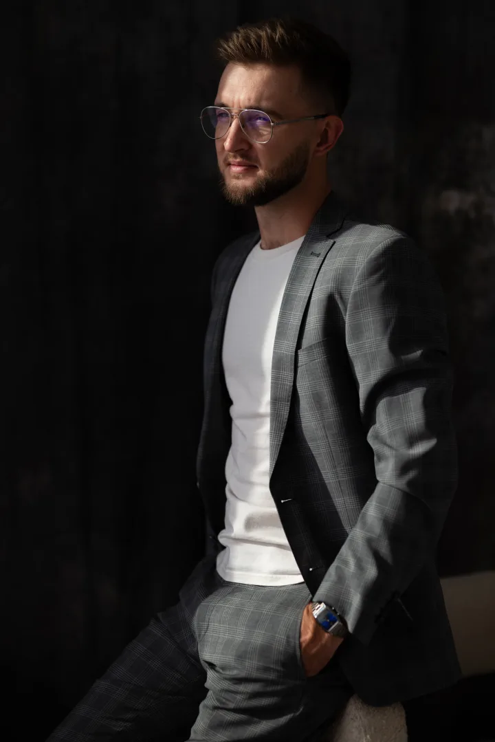 Dmytro Kolida in a grey suit against a dark studio background